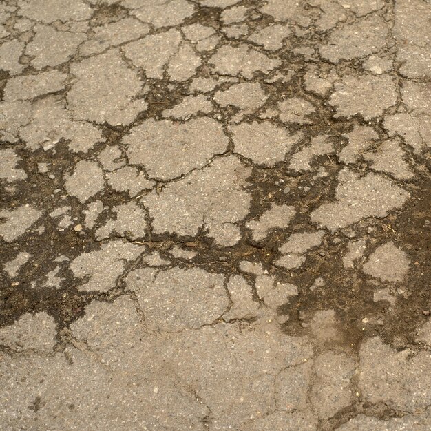 Foto vista de cima de close-up de uma imagem de estrada de concreto cinza quebrada e rachada