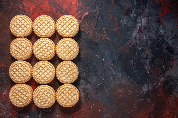 Vista de cima de deliciosos biscoitos dispostos em fileiras do lado direito no fundo de cores misturadas com espaço livre