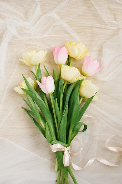 Vista de cima de flores de tulipa cor rosa e amarela com espaço de cópia em fundo bege para mulheres