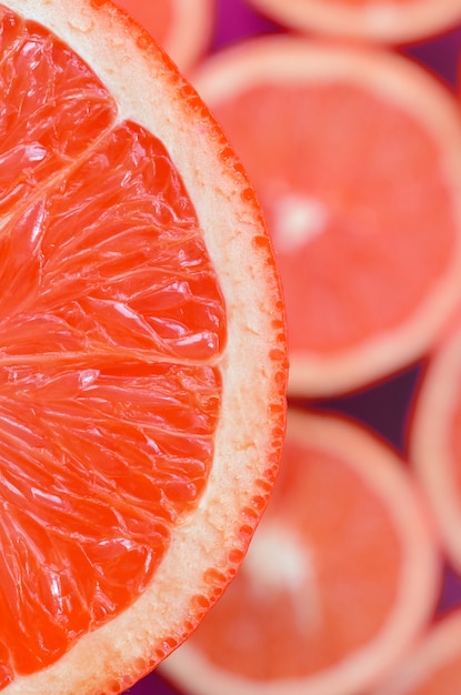 Vista de cima de um fragmento da fatia de toranja vermelha no fundo de muitas fatias de toranja turva