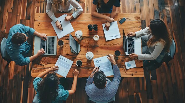 Vista de cima de um grupo de jovens profissionais de negócios trabalhando juntos em uma mesa de madeira