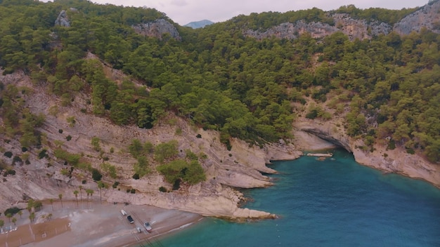 Vista de cima de uma costa rochosa coberta de árvores verdes Caverna na rocha Água azul clara Seascape