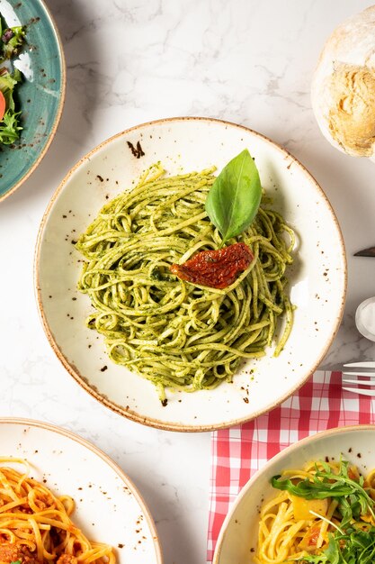 Vista de cima de vários pratos de comida italiana, especialmente macarrão com pesto.