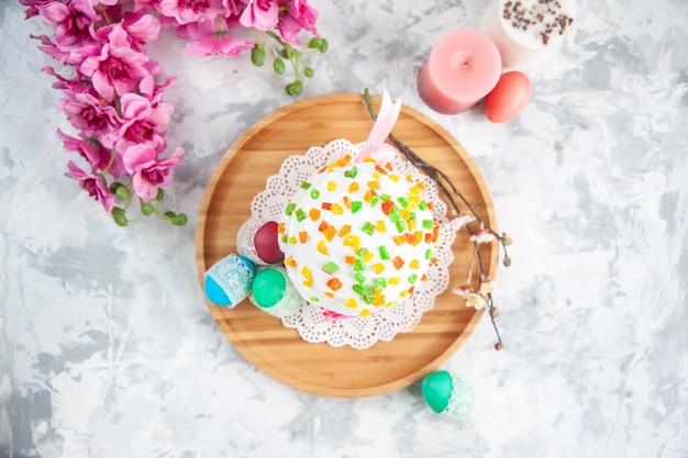 vista de cima delicioso bolo de páscoa com frutas secas e ovos coloridos na superfície branca