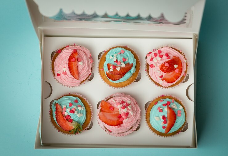 Foto vista de cima em lindos cupcakes coloridos com granulado e morango na caixa