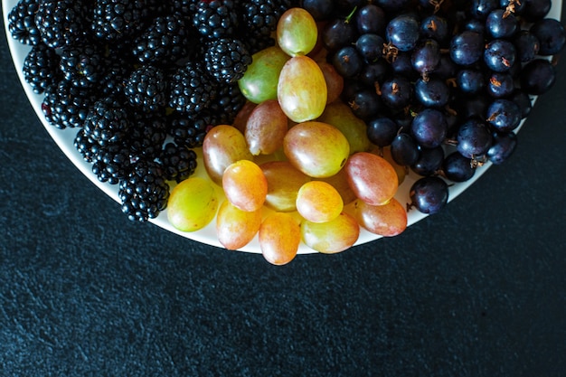 Vista de cima. Mistura de frutas em um terrel branco. Separação de triângulo. Mistura de verão de frutas. Layout elegante de bagas