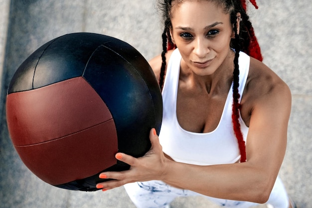 Vista de cima Mulher atlética com bola médica Força e motivaçãoFoto de mulher esportiva em roupas esportivas da moda