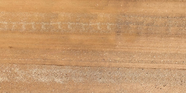 Vista de cima na textura da estrada de cascalho com marcas de pneus de carro