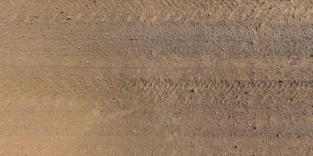 Vista de cima na textura da estrada de cascalho com marcas de pneus de carro