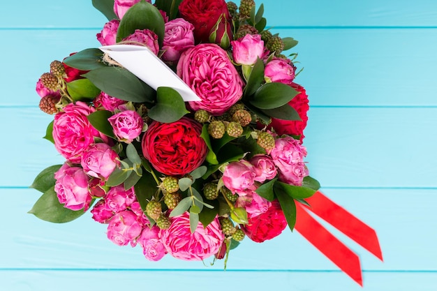 Vista de cima no lindo buquê de rosas cor de rosa e vermelhas com uma etiqueta de presente em branco com espaço de cópia e fita vermelha em uma caixa preta circular. Dia dos namorados e conceito de aniversário