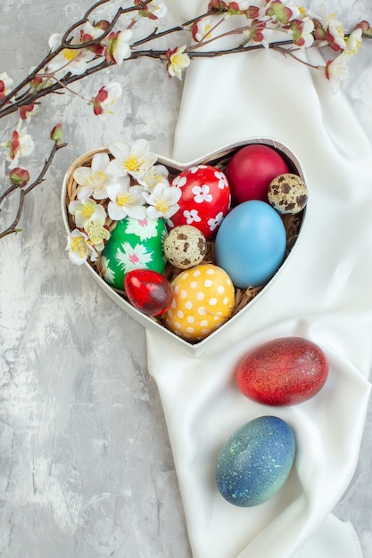vista de cima ovos de páscoa coloridos dentro de uma caixa em forma de coração na superfície branca