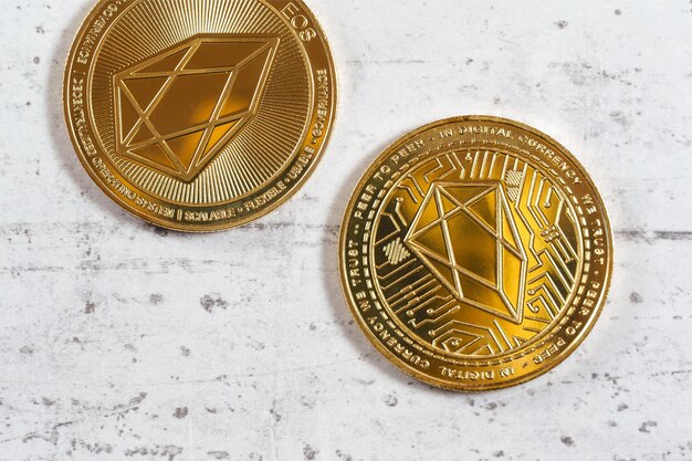 Vista de cima para baixo, detalhe da criptomoeda EOS - EOSIO comemorativa dourada - moedas na placa de pedra branca.