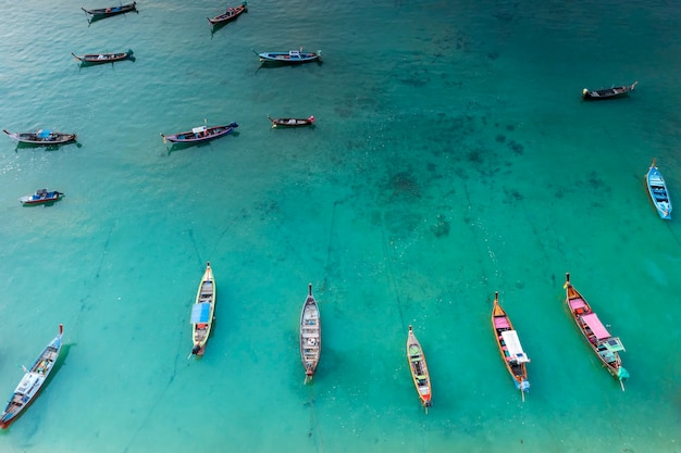 Foto vista de cima para baixo do drone aéreo dos barcos de pesca na costa durante a maré baixa. vista de cima muitos barcos de pesca longtail tradicionais tailandeses no mar tropical.