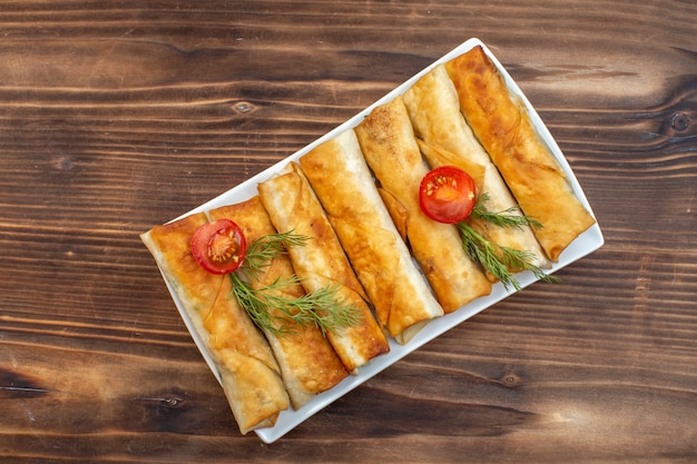 vista de cima pastéis de verduras fritas com verduras e tomates dentro do prato