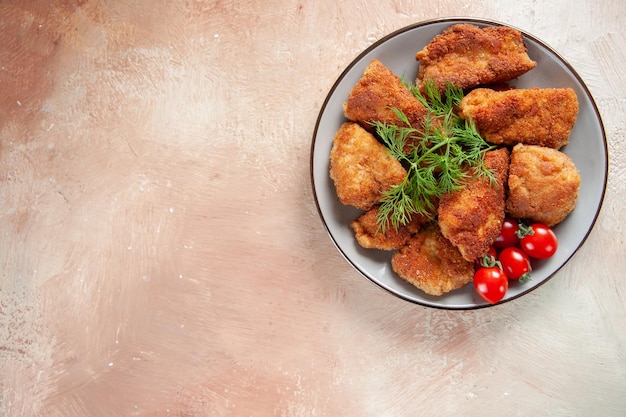 Vista de cima saborosas asas de frango com verduras dentro do prato em superfície clara