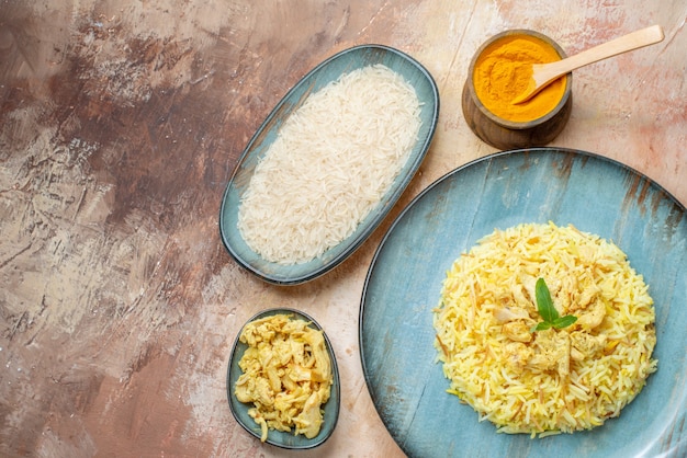 vista de cima saboroso plov em prato redondo arroz cru frango molho de cebola em travessas açafrão em uma tigela pequena no espaço livre da mesa