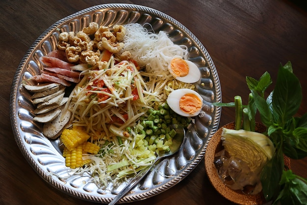 Foto vista de cima salada de mamão ou som tum em comidas tailandesas com porco azedo e ovo cozido.