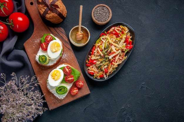 Vista de cima sanduíches de ovo saborosos com tomate e salada de pimenta na tábua fundo escuro almoço torrada lanche hambúrguer sanduíche comida pão refeição