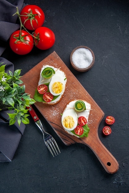 vista de cima sanduíches saborosos com tomates, pepinos e ovos na tábua de corte fundo escuro hambúrguer comida lanche torrada refeição sanduíche