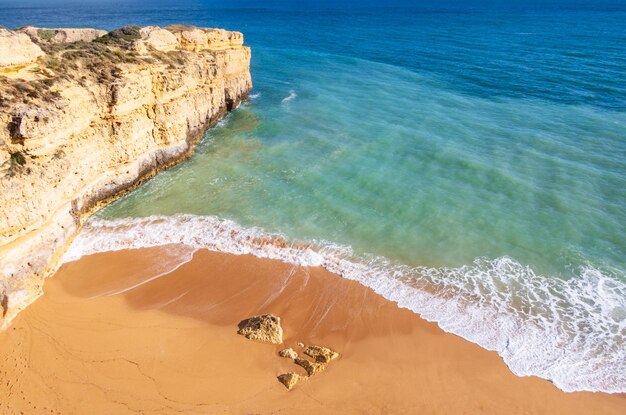 Foto vista de cima sobre o oceano e ondas esmagando na praia de areia no algarve, portugal