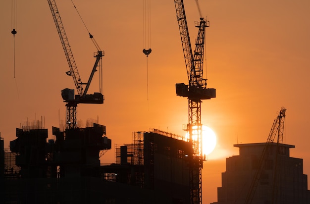 Vista de construção de silhueta de guindastes ao pôr do sol