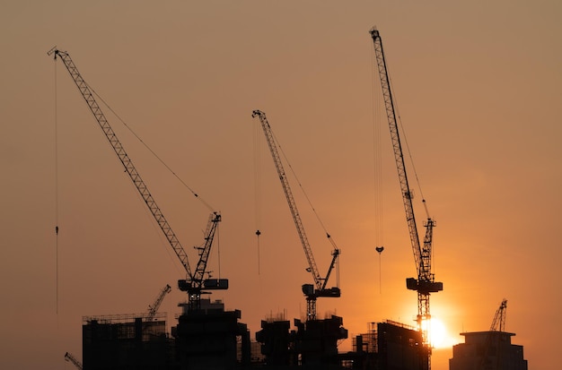 Vista de construção de silhueta de guindastes ao pôr do sol