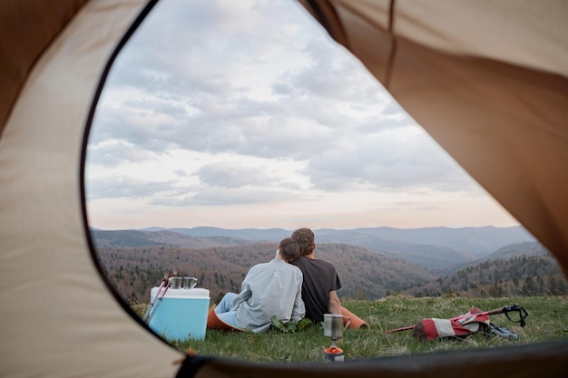 Vista de dentro da tenda de um casal apaixonado abraçando e descansando no pico da montanha Bela natureza