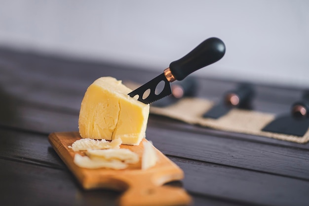 Vista de detalhes de cloesup composta de queijo cheddar envelhecido com faca de queijo sobre pano de fundo de madeira marrom vintage