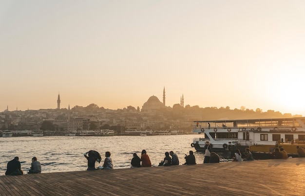 Vista de istambul a partir do dique ao pôr do sol. as pessoas assistem ao pôr do sol e a vista panorâmica de istambul do cais