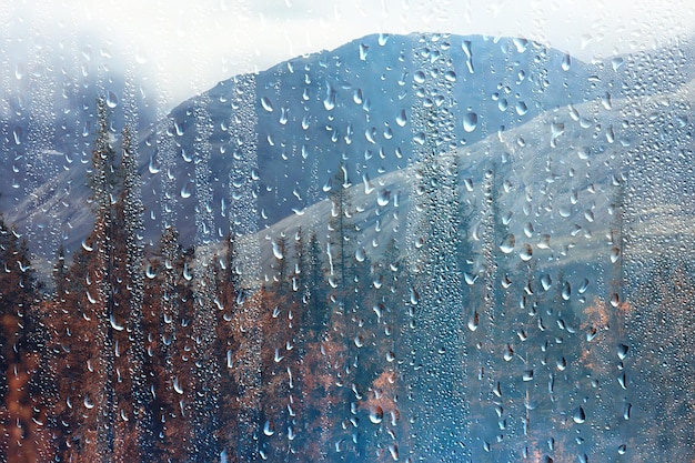 vista de janela de chuva, gotas de água no vidro, vista de floresta e montanhas de fundo de paisagem
