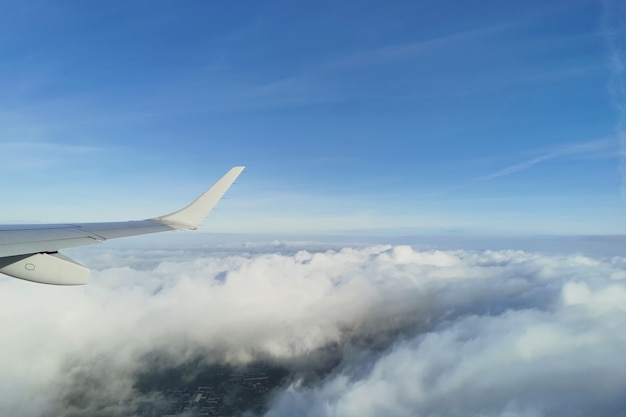 Vista de nuvens brancas fofas no céu azul sob a asa do avião