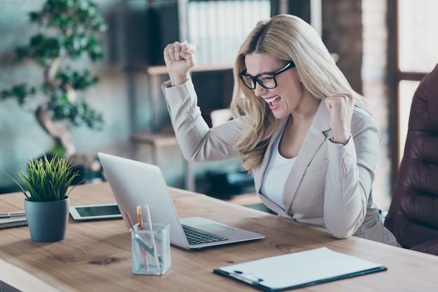 Vista de perfil de mulher de negócios aparência de notebook tela de laptop levantando os punhos