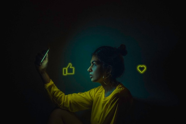 Vista de perfil de mulher usando telefone com ícones na sala escura