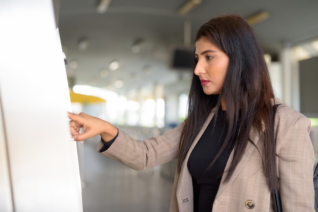 Vista de perfil de uma linda jovem empresária indiana comprando passagem na estação de skytrain