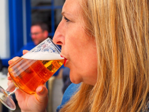 Vista de perfil de uma mulher bebendo cerveja em um copo de vinho