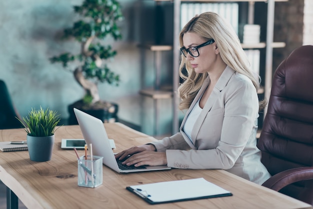 Vista de perfil de uma senhora de negócios confiante digitando no PC