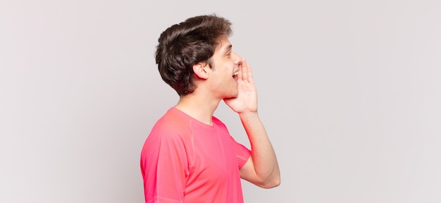 Vista de perfil do menino, parecendo feliz e animado, gritando e chamando para copiar o espaço ao lado