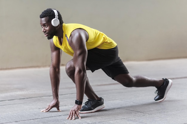 Vista de perfil homem atleta africano em pose de início de corrida