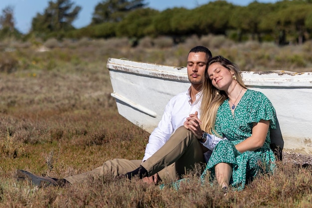 Vista de perto de um jovem casal europeu feliz segurando junto ao lado de um barco de madeira