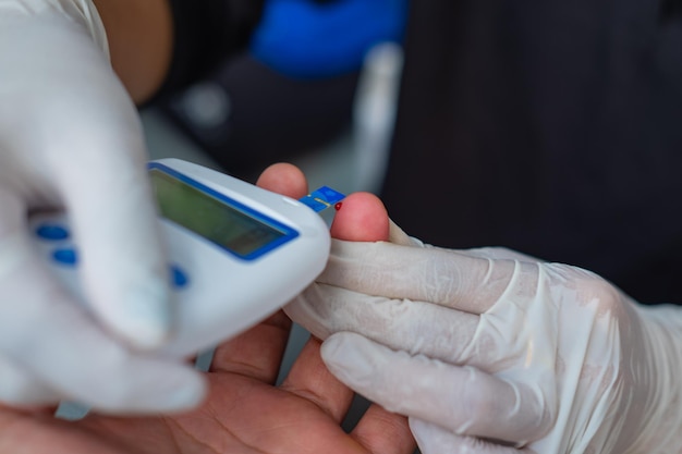 Vista de perto de um trabalhador médico verificando a amostra de sangue de um paciente com um kit de medidor médico