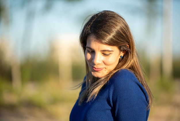 Foto vista de perto de uma mulher alegre olhando para baixo e sorrindo enquanto desfruta ao ar livre em um parque