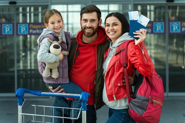 Vista de retrato da cintura para cima da família e crianças com bagagem no terminal do aeroporto voam juntos nas férias Garota feliz segurando o brinquedo e se sentindo feliz