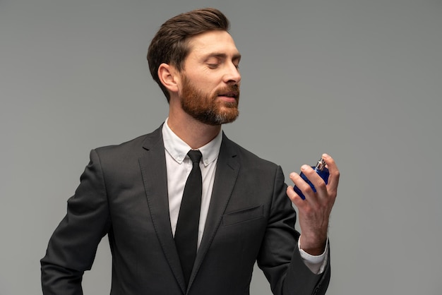 Foto vista de retrato da cintura para cima do homem de terno profissional apresentando produto de perfume masculino isolado no anúncio de espaço de cópia cinza