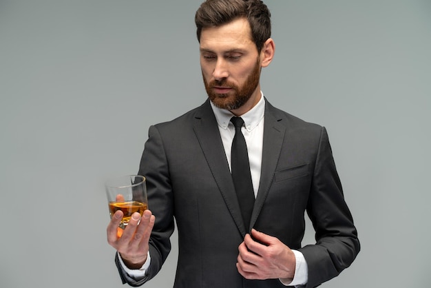 Vista de retrato da cintura para cima do olhar bonito e atraente para o uísque do copo em suas mãosConceito de homens elegantes e bem-sucedidos