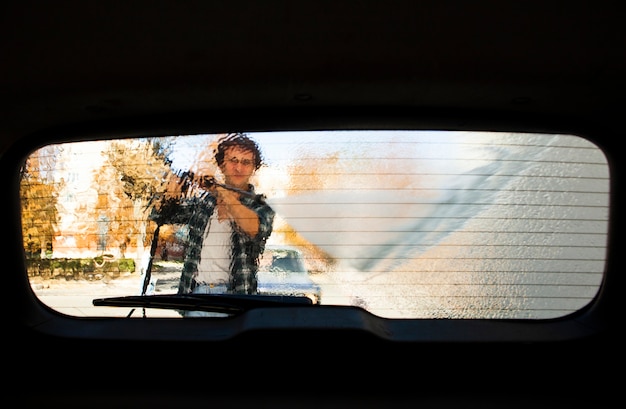 Foto vista de silhueta de homem lavando uma janela de carro