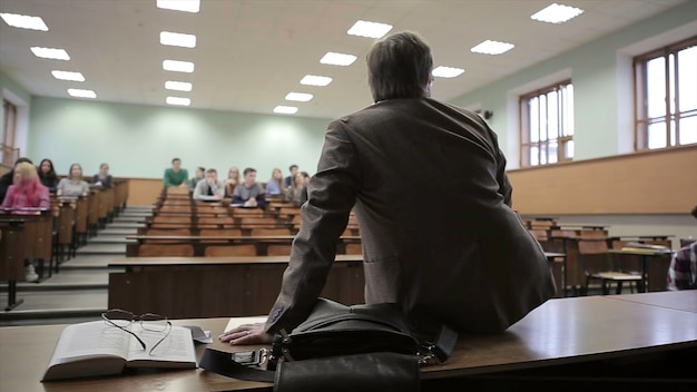 Vista de trás de um homem apresentando a alunos em um teatro de palestras vista de trás do professor que