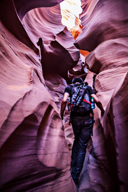 Foto vista de trás de um homem caminhando em meio a formações rochosas