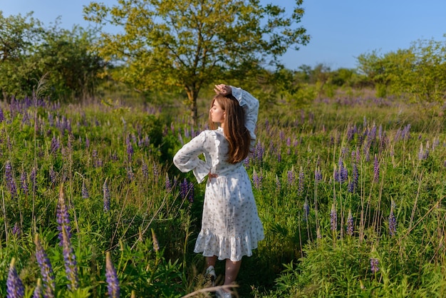 Foto vista de trás de uma jovem de vestido elegante caminhando em um campo de lúpulos