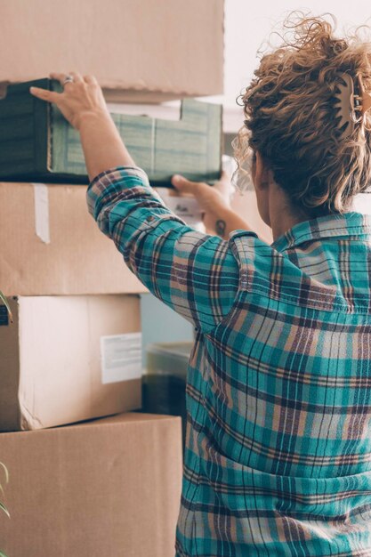 Vista de trás de uma jovem mulher desempacotando depois de se mudar para uma nova casa Conceito de caixas de papelão e trabalho para se mudar e mudar de casa Novo conceito de vida Empréstimo e hipoteca economia Independência dama lazer