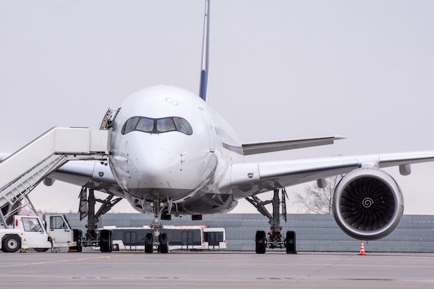 Vista de um avião de passageiros de longo alcance no aeroporto com uma rampa no estacionamento.